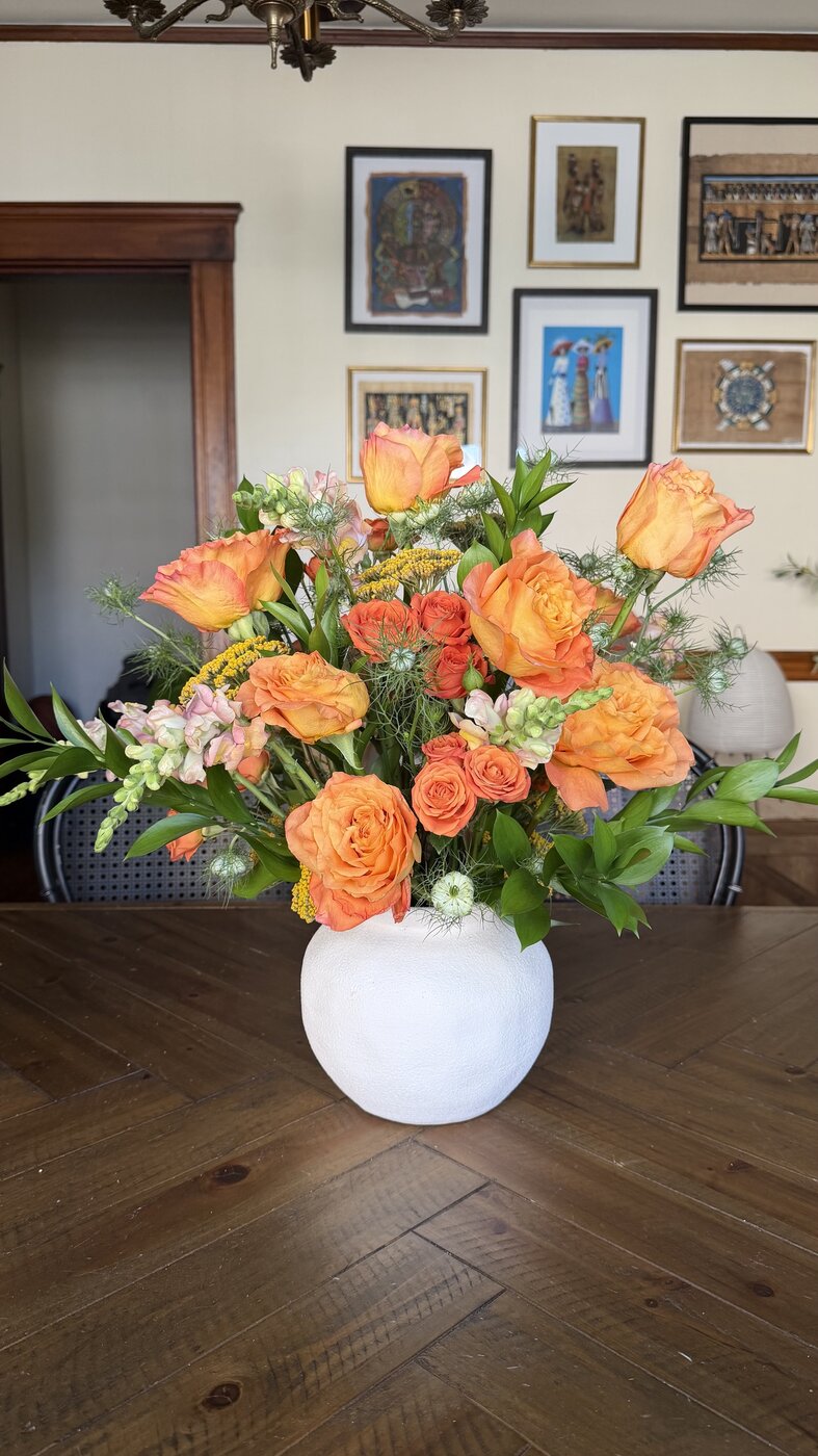 Peach and apricot rose arrangement in a round white vase