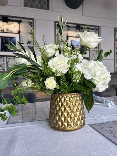 Close-up of a white rose and hydrangea arrangement in a gold vase